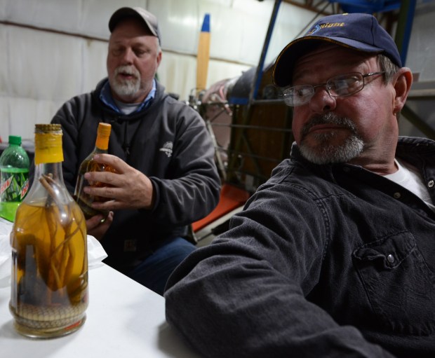 Skip Turner (right) eyes a corba and scorpion embalmed in a bottle.   